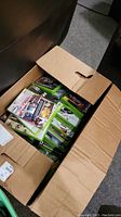 Box partially open showing many green Xbox 360 game cases inside with visible front cover artwork of multiple games.