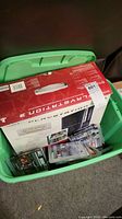 Green plastic tote with PS3 retail box and loose PS3 game cases