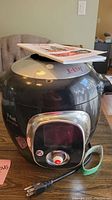 Front view of black T-fal Cook4me electric cooker showing lid and partial digital control panel with cord.