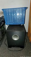 Yamaha speaker unit with a blue plastic bin placed on top, seen from front.