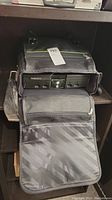 Photo showing the Original Xbox console inside the travel bag, front view with disc tray and controller ports.