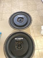 Top view photo of two 15-inch vintage Dukane subwoofers showing the cones, surrounds, and central sound diffuser with brand and patent marking.