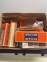 Empty Lionel Electric Trains boxes in a larger brown box with various sizes stacked inside, showing orange and cream color scheme with blue logo