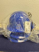 Three blue Pyramex hard hats still sealed in plastic bags, stacked together