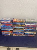 Photo showing stacks of 55 children's DVDs, including titles such as Frozen, Finding Nemo, and multiple Disney movies.
