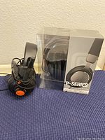 Black web headphones with attached mic sitting on a table next to boxed P-Series headset