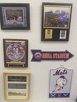 Overall view of seven Mets memorabilia items including framed photos and signs on a wall.