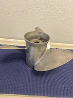 Photo showing the propeller blades and hub resting on a blue mat with visible oxidation and surface wear.