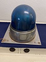 Front photo of blue dome rotating beacon light showing scratches and blue dome with metal base