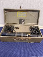 Overall view of the projection pointer inside its carrying case with the lid open showing the main device and other accessories.