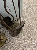 Fireplace tools set including poker, shovel, and brush placed in cast iron stand