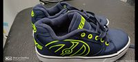 View of navy blue Heelys shoe showing neon green logo and eyelets