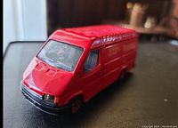 Close up of red vintage Corgi Ford Transit van showing front and side details.