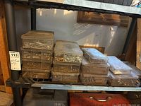 13 plastic storage cases stacked on a metal shelf with various nails, screws, bolts, and springs visible inside.