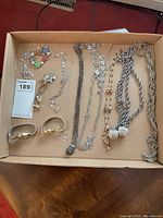 Overview of necklaces, sweater clip, and other jewelry items arranged in a box.