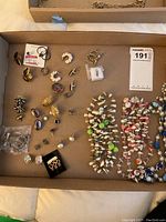 Full overview of necklaces and assorted earrings and pins arranged on cardboard.