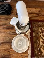 White mixer base and head separated from bowls, two white mixing bowls visible foreground