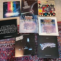 Photo showing nine distinct movie soundtrack vinyl albums displayed on a patterned carpet with bright and dark colors, covers visible including Star Trek, Star Wars, Rick Wakeman's works, Superman, and Hit Movie Themes.