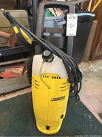 Front view of yellow Karcher K 3.86 power washer showing main body, hose wrapped around, and spray wand positioned on top.
