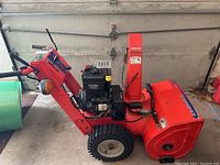 Side view of entire snowblower showing frame, engine, auger housing and tires