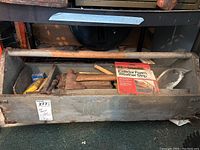 Photo showing metal tool carrier with handle filled with various tools including hammers, weather stripping, and an Exacto cutter