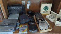 Lot showing various audiovisual items including headphones, portable CD players, Sony Walkman, cassette rewinder, and small speakers.