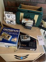 Full lot on table showing cameras with boxes, disposable cameras, and camera bag