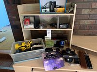 Shelf display showing boxed cameras, boxes and accessories on top and middle shelves