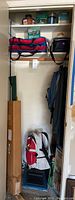 Full closet view showing various backpacks, a jacket, and a fishing pole case along with other gear on shelves and floor.