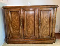 Front view of wooden buffet with three paneled doors and metal pull handles.