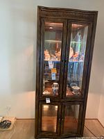 Full view of the Drexel Heritage curio cabinet with glass doors showing interior shelves and lighting.