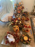 Overall lot view showing eleven faux floral fall centerpieces and decor including a large clear glass bowl