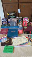 Overall view of collection of boxed and loose board and card games displayed on carpeted floor.