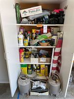 Full view of garden supply cabinet with garden chemicals, gloves, oils, watering cans, and flag