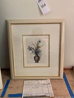Framed etching showing the dragon-themed vase with iris and orchid flowers, cream colored frame with gold trim.