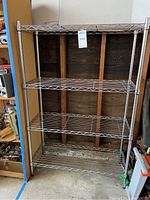 Full view of the assembled 4-tier steel wire rack shelving unit, showing four wire shelves supported by tubular metal posts.