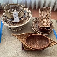 Photo showing various stacked wicker baskets including an oval, round tray, and rectangular shapes in natural and stained finishes.