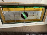 Full view of the antique stained glass panel framed in wood, showing the geometric and colorful design.