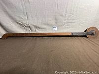 Full view of the antique garden edger tool showing long wooden handle and iron blade wheel.