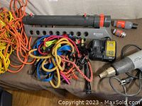 Overall view of assorted tools including cords, heat tool, charger, hose connectors, and garden sprinkler