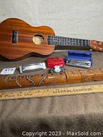 Ukulele, harmonicas, and African flute laid out with a ruler for size reference