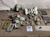 Overview of the lot showing glass, crystal, and ceramic door knobs along with metal mounting plates and lock boxes