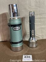Full view of the vintage Stanley thermos and 1950s Satellite flashlight by Burgess side by side showing size and general condition