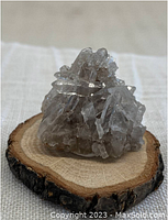 Front view of translucent grayish Himalayan Quartz crystal cluster on wooden base slice