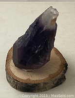 Front and angled view of the natural amethyst crystal mounted on a round wooden base, showing crystal texture, purple color, and natural inclusions.