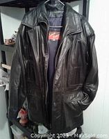 Front view of black leather jacket with collar, zipper front hidden by flap and pockets.