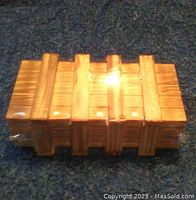 Top view of the wooden puzzle box wrapped in clear plastic, showing the wood grain and puzzle notches.