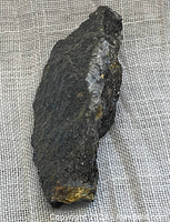 Natural pyrite mineral specimen placed on a beige fabric background showing side and top views.