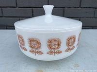 Front view of vintage white milk glass casserole dish with brown sunflower pattern and lid, showing overall condition and design.