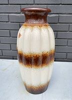 Front view of large ceramic vase showing brown and cream glaze with fluted vertical design and flared rim.
